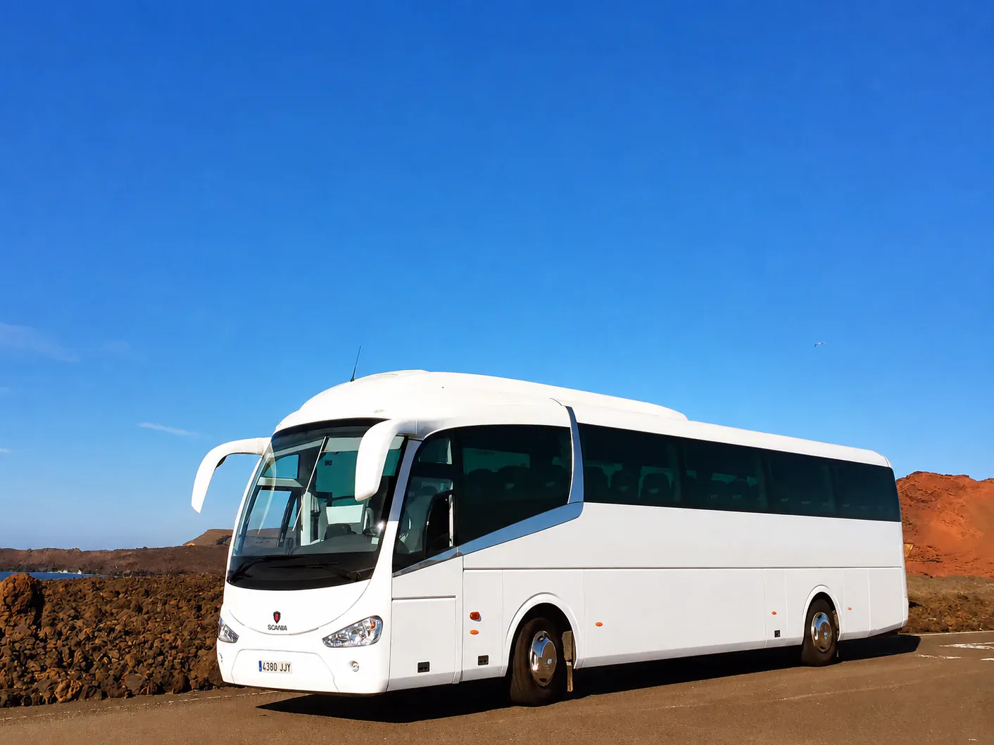 White BusCom Irizar coach under a deep blue Spanish sky, for groups in Barcelona