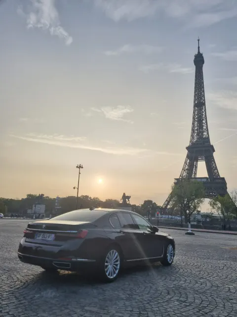 BMW Serie 7 nera con la Torre Eiffel al tramonto